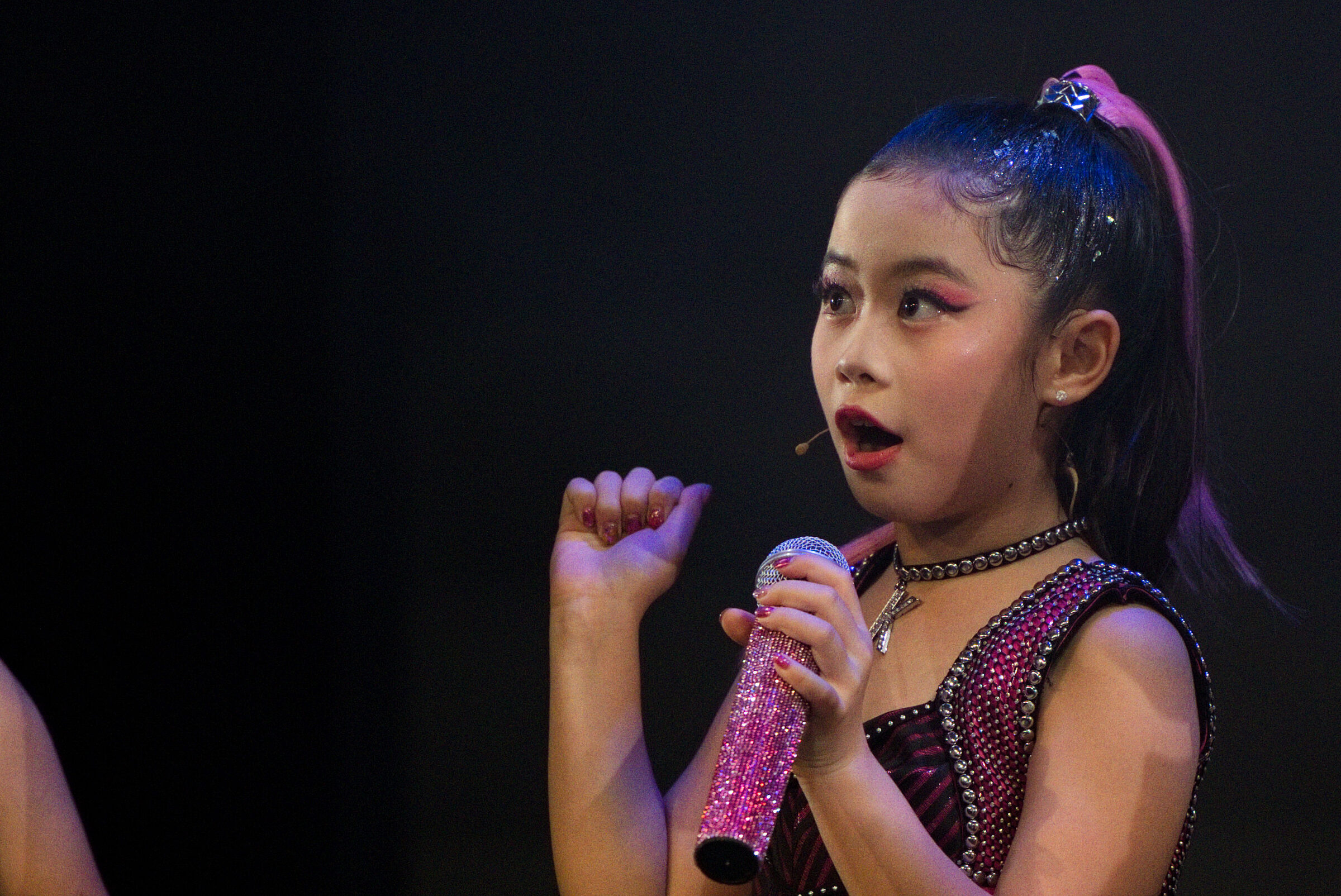 Candid close-up of young performer singing with headset mic on stage, Six: Teen Edition